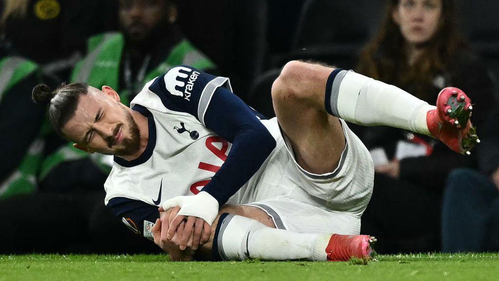 Spurs centre-back Radu Dragusin holding his knee