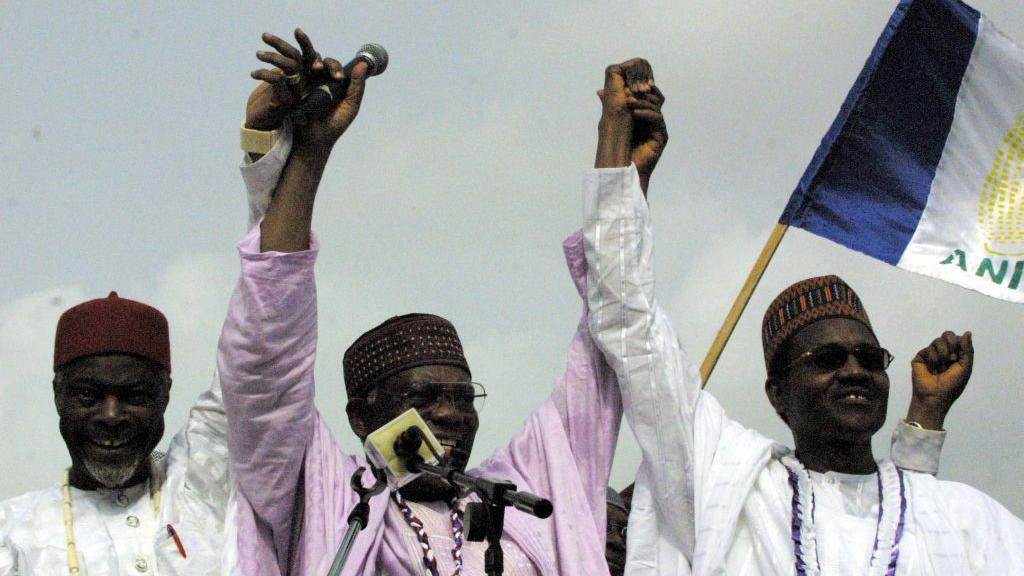 Buhari, his running mate Chuba Okadigbo and Chairman of the All Nigerian Peoples Party Don Etiebet, smile and raise their joined hands above heads.
