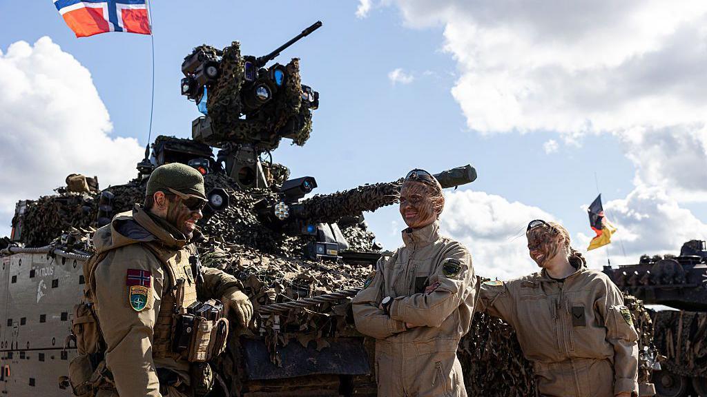 Nato troops from Denmark and Norway stand in front of a tank during exercises in May 2025