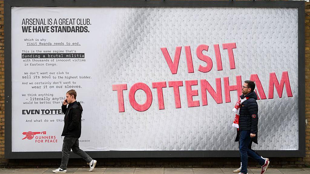 Fans walk past a 'Visit Tottenham' sign outside Emirates Stadium