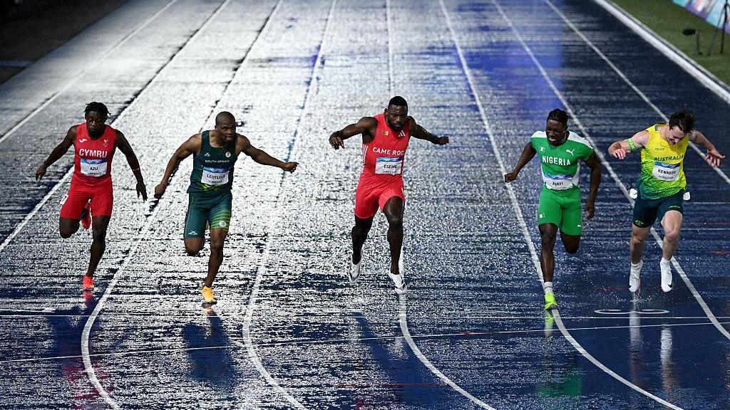 Jeremiah Azu of Team Wales, Gift Leotlela of Team South Africa, Emmanuel Eseme of Team Cameroon and Kayinsola Ajayi of Team Nigeria cross the finish line in the Men's 100 Metres Final 