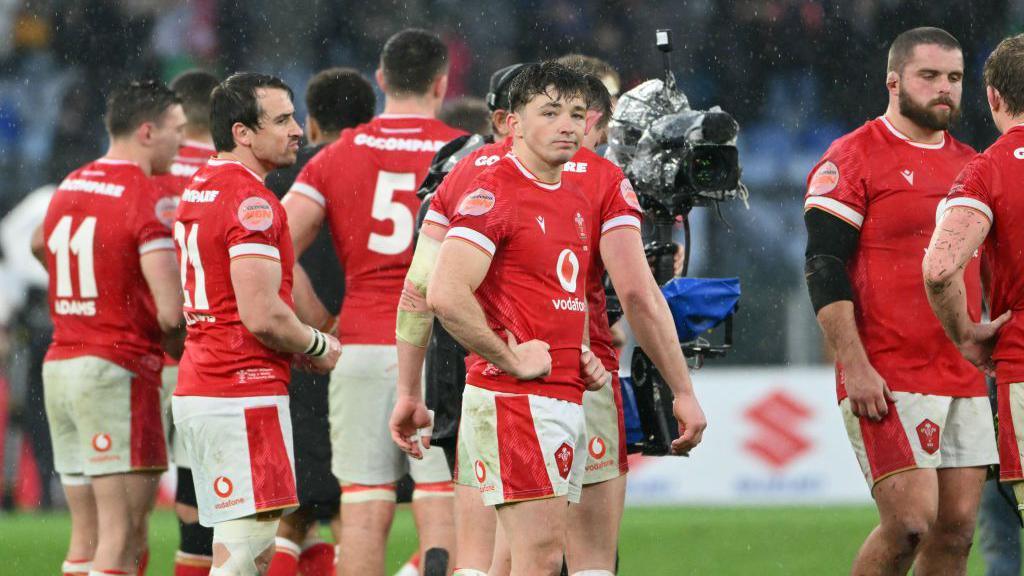 Dan Edwards looks disappointed with Wales players behind after loss in Italy