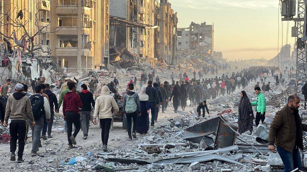 Palestinians in Jabalia walk among debris as they return to their houses after the announcement of ceasefire and hostage-prisoner swap deal between Hamas and Israel