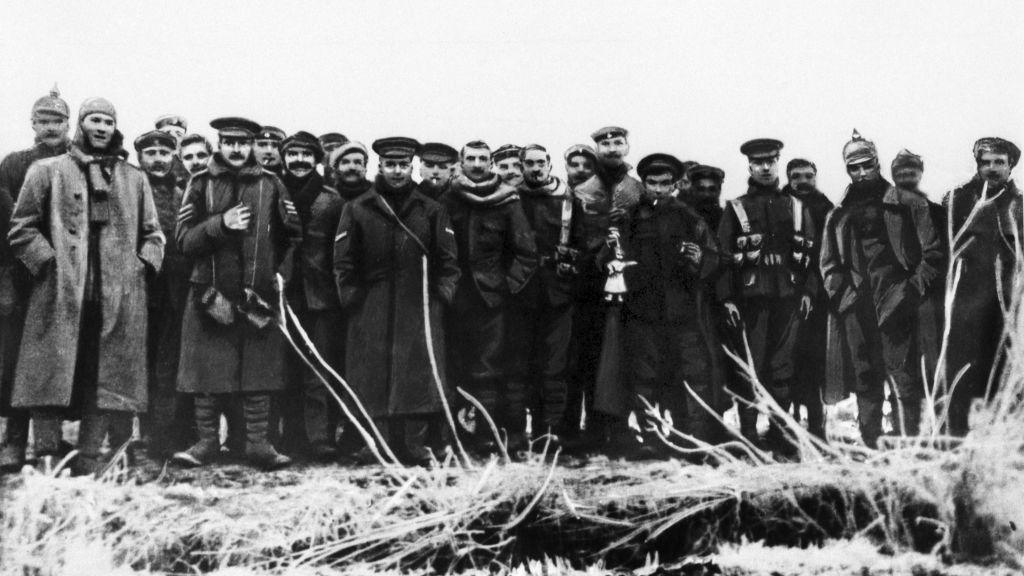 Black and white photograph of soldiers, standing in a group in a field, wrapped up against the cold, looking at the camera.