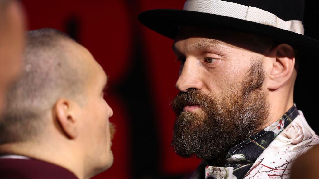 Oleksandr Usyk and Tyson Fury face off during a news conference.