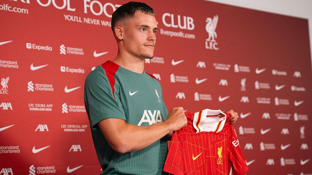 Florian Wirtz holding up a Liverpool shirt