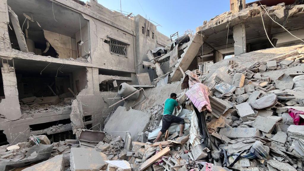 A Palestinian man searches for missing family members under the rubble of a building destroyed by an Israeli strike, in Beit Lahia, in the northern Gaza Strip (7 November 2024)