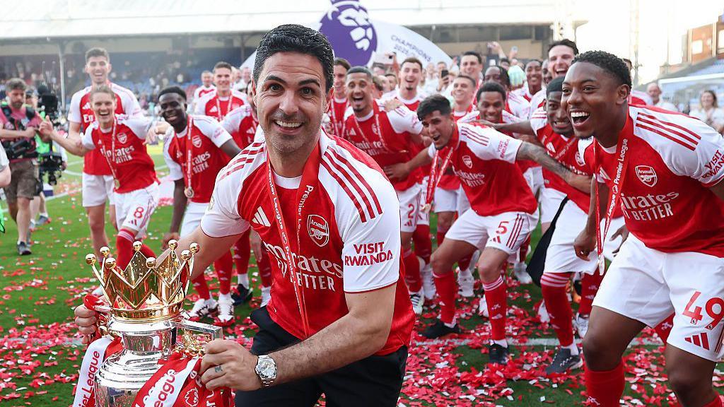 Arsenal manager Mikel Arteta celebrates with the 2025-26 Premier League trophy in front of his jubilant players