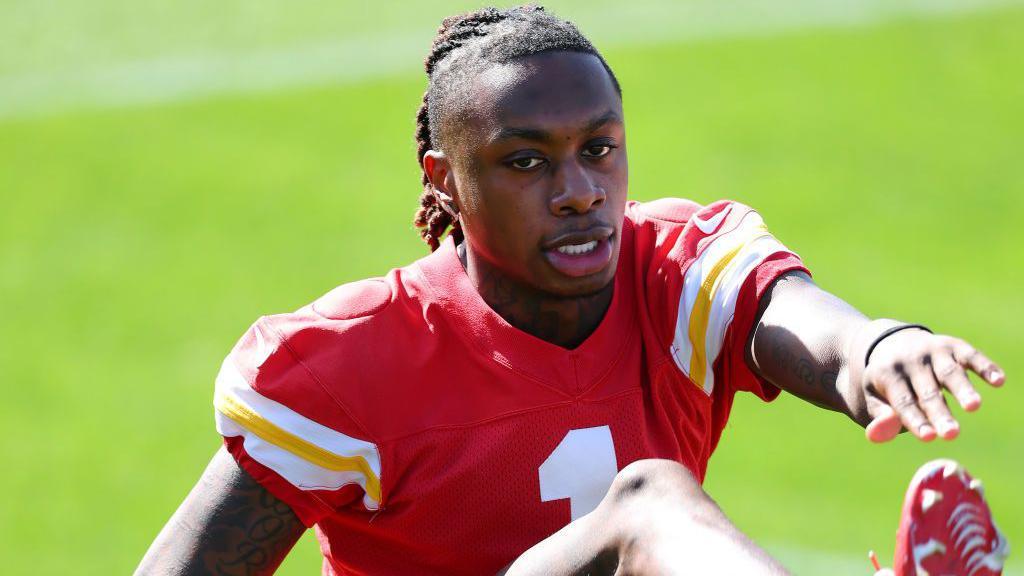 Chiefs speedster Xavier Worthy stretches his hamstrings in practice