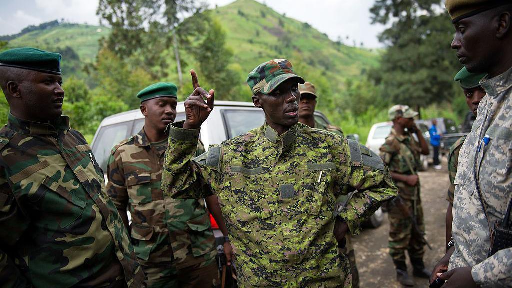 Sultani Makenga, dressed in military fatigues, addresses a group of fighters