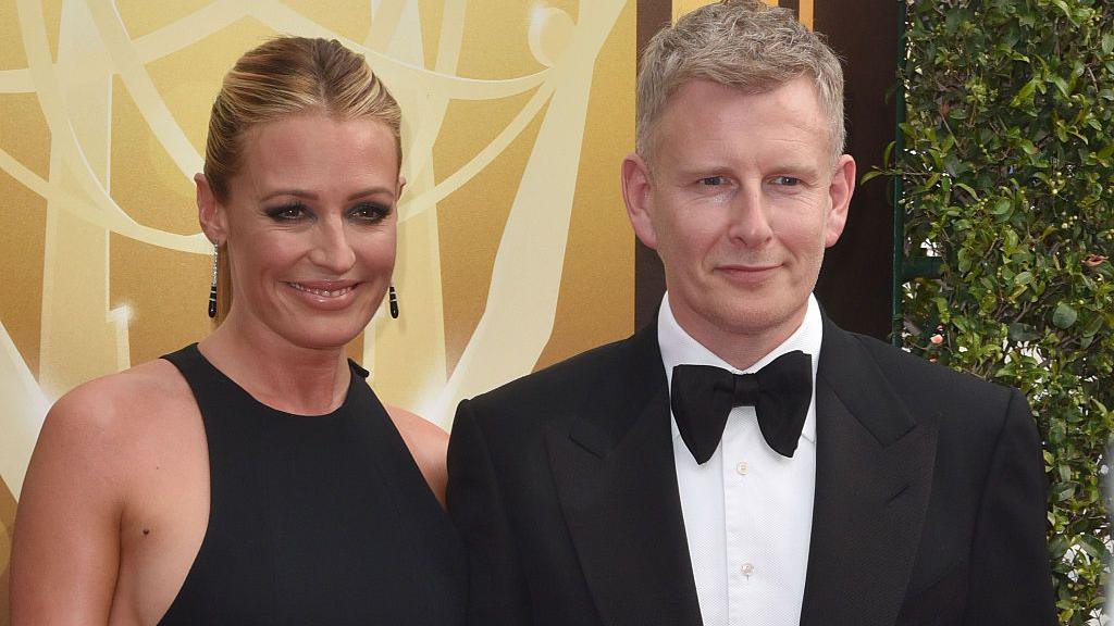 Cat Deeley and Patrick Kielty pose in front of a yellow background.