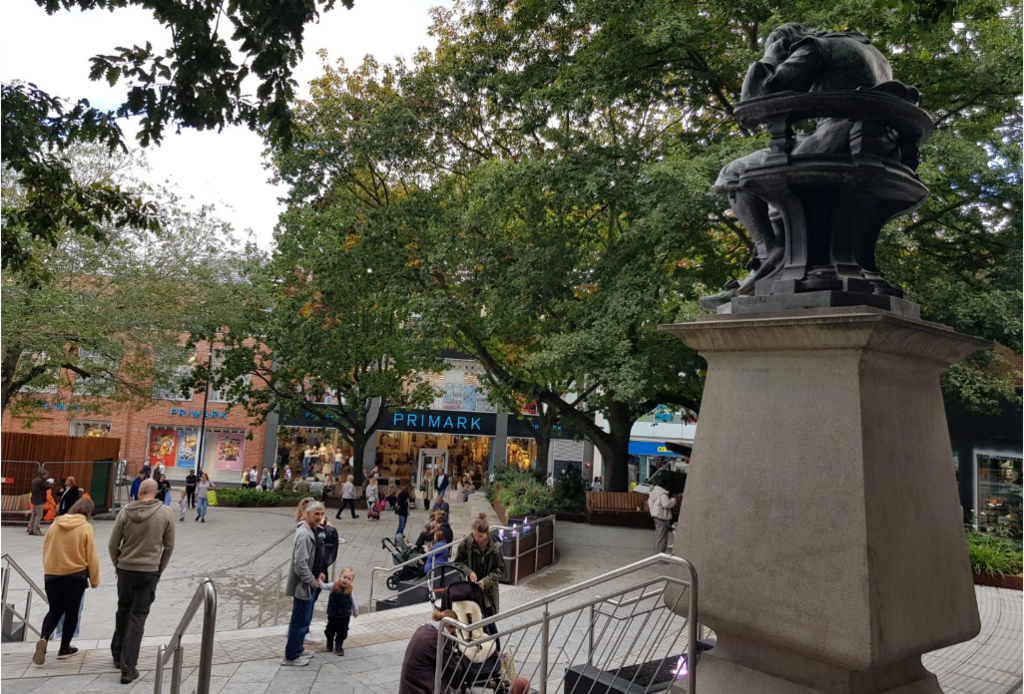 Renovated Hay Hill showing metal guide rails for steps, Sir Thomas Browne statue, trees, people standing around and Primark shop in background