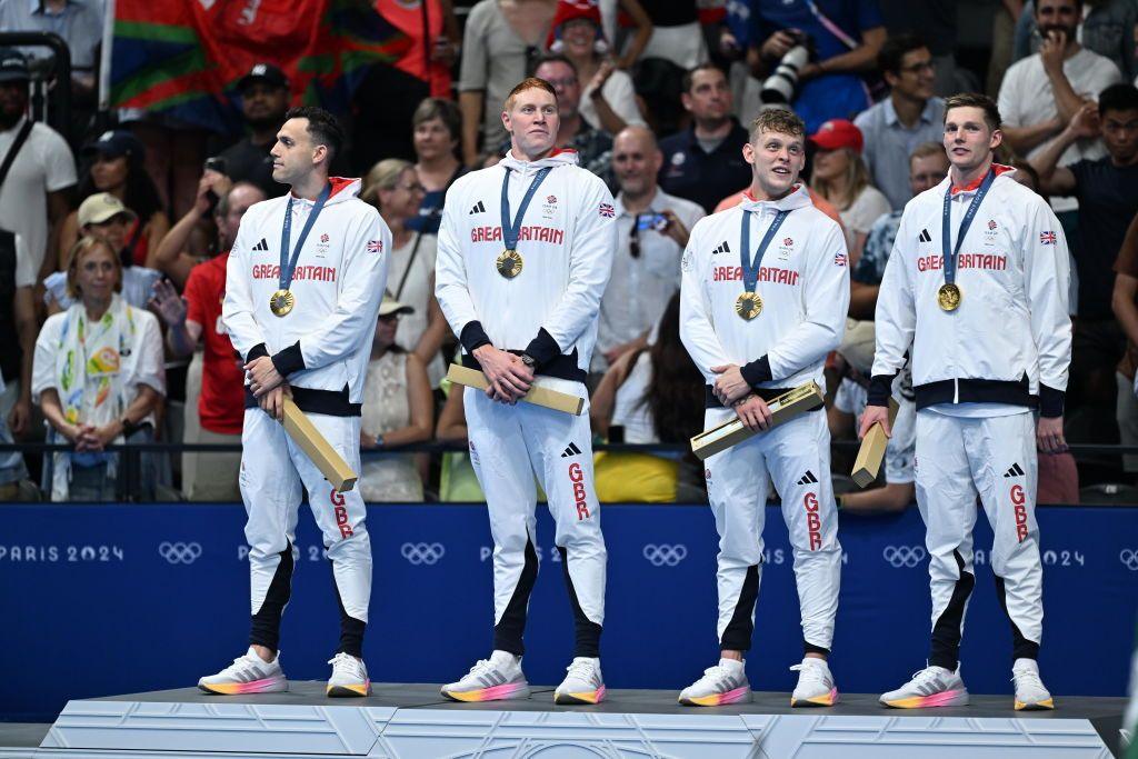 Tom Dean receives his Olympic gold medal with his teammates after winning in the men's 4x200m freestyle relay final.