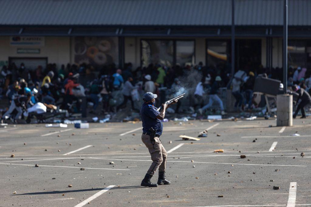 A police officer shooting rubber bullets at crowds of people 