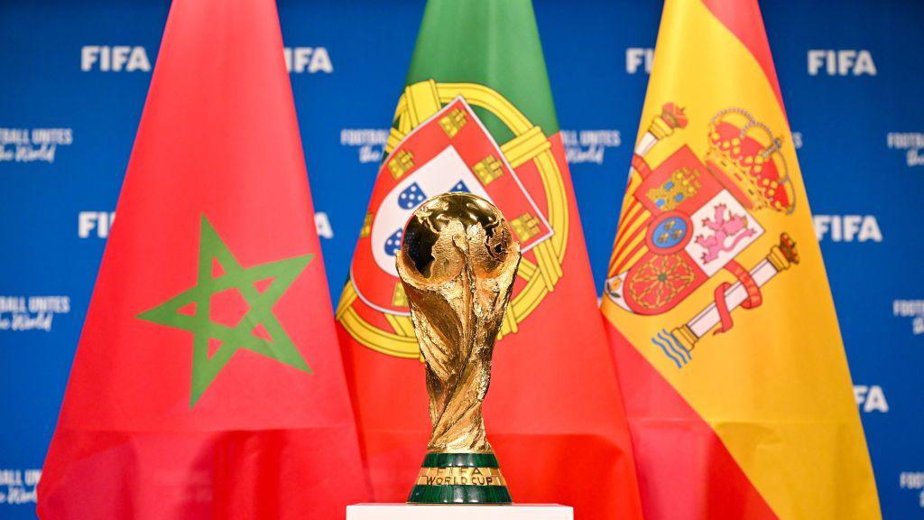 Fifa World Cup trophy standing in front of the flags of Morocco, Portugal and Spain.