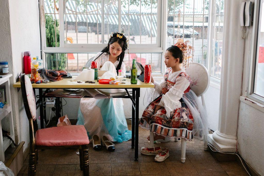 Two young women wearing traditional Chinese attire sit inside a massage parlour in Cyryldene, the Chinese district of Johannesburg, South Africa - Saturday 8 February 2025.