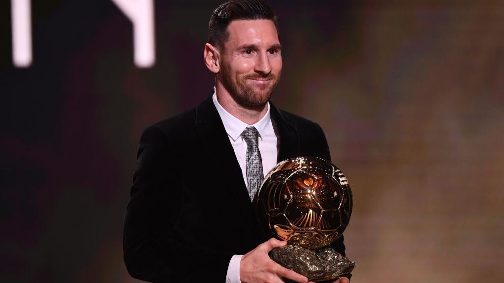 Lionel Messi holds the 2019 Ballon d'Or trophy at an awards ceremony in Paris.