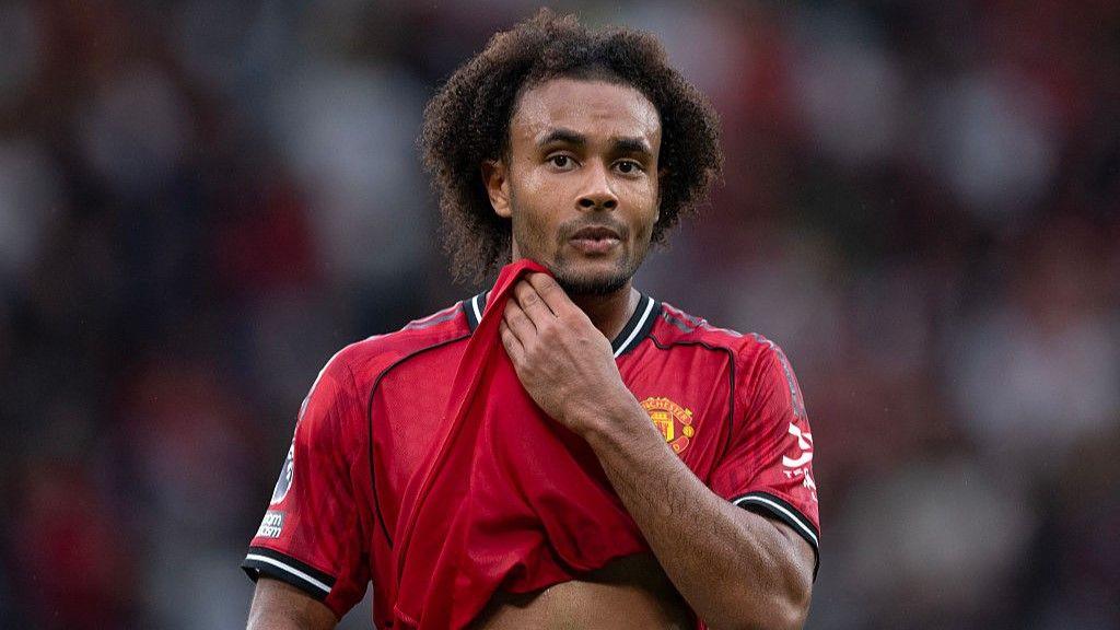 Joshua Zirkzee holds part of shirt and looks on during match for Manchester United