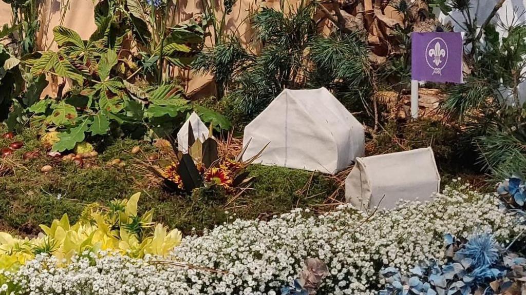 Model tents and a Scout flag sit amongst vegetation including Gysophila and moss