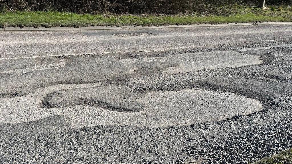 A series of large potholes next to each other on a road.
