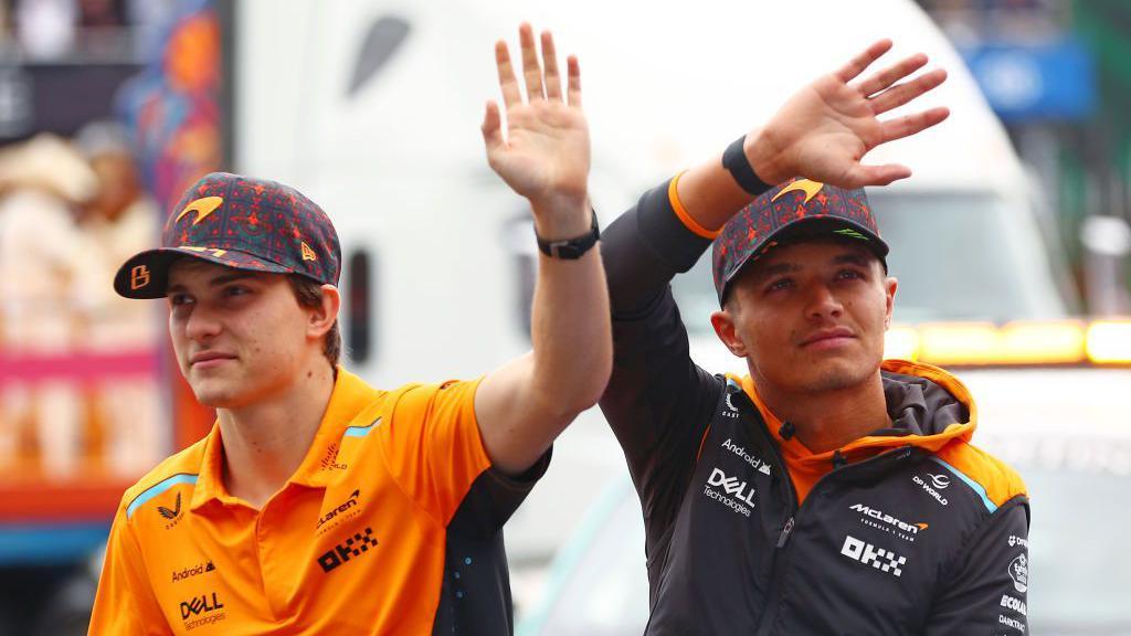 McLaren drivers Oscar Piastri and Lando Norris wave to fans