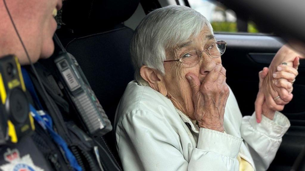 A woman holds her hand to her face while laughing - alongside police officers