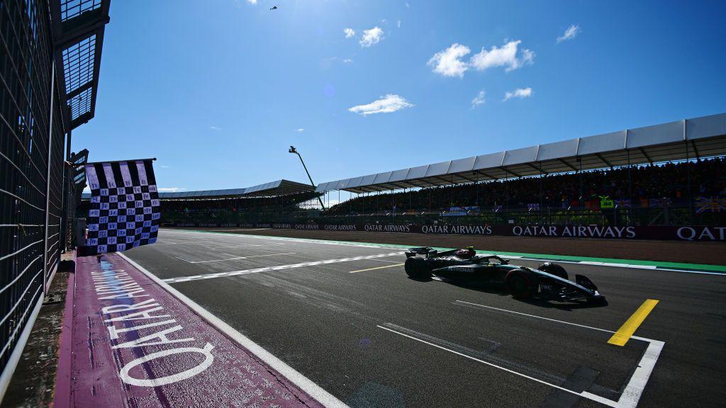 The chequered flag is waved as Lewis Hamilton crosses the finish line on the 'Hamilton Straight' at the British Grand Prix in 2024