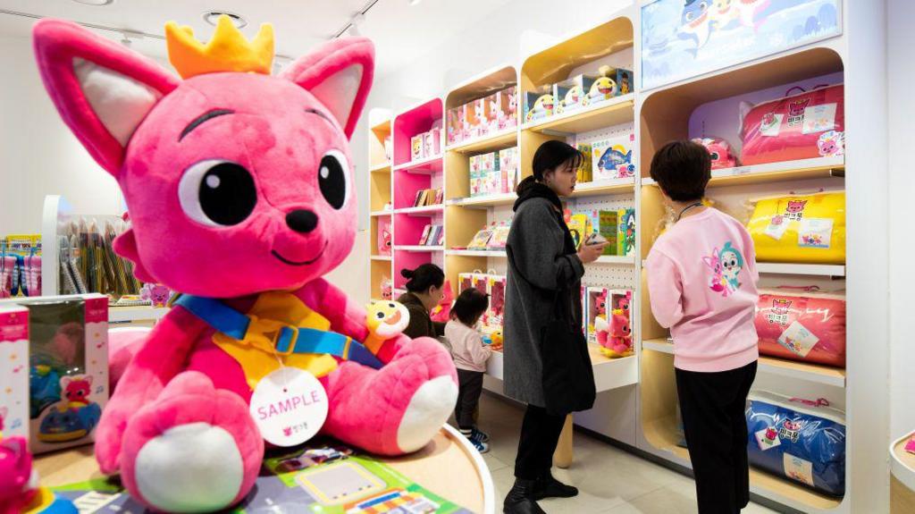 Customers browse at toys as a giant doll of the company's Pinkfong fox character is displayed at the firm's store in South Korea