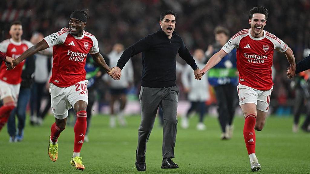 Noni Madueke, Mikel Arteta (Arsenal Manager) and Declan Rice of Arsenal holding hands and running across the pitch after winning the game