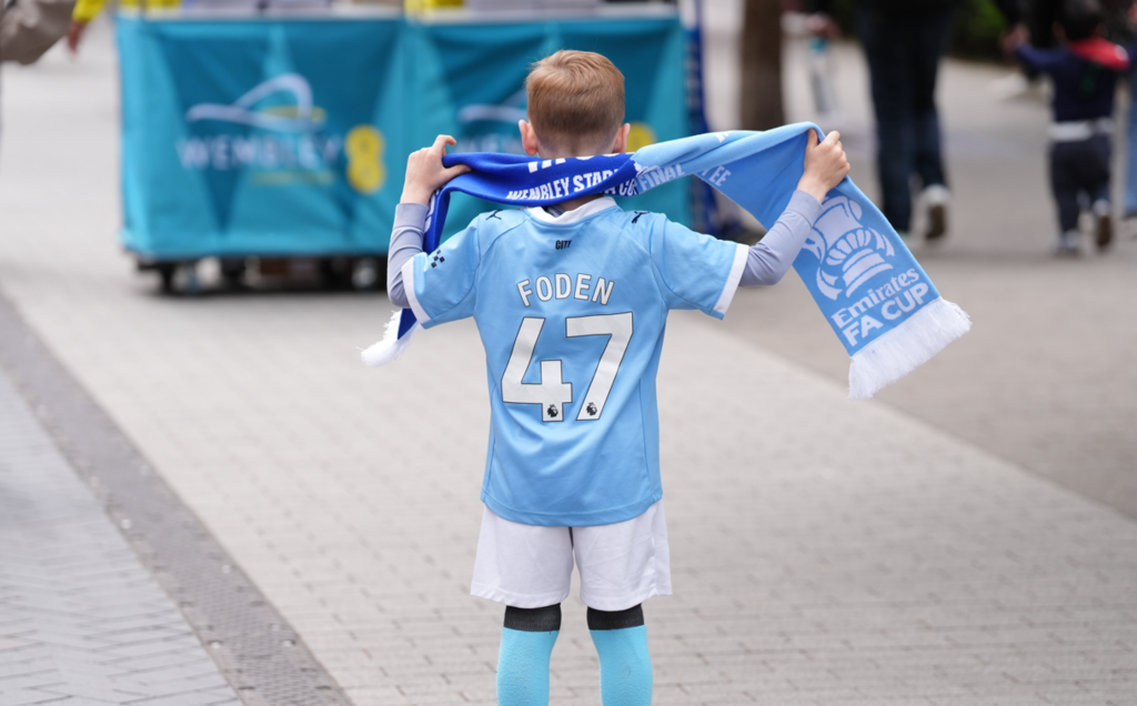 A child in Manchester City strip with a half and half City and Chelsea scarf