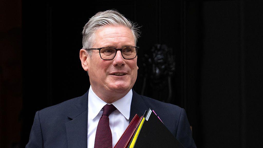 Prime Minister Sir Keir Starmer seen leaving Downing Street carrying folders.