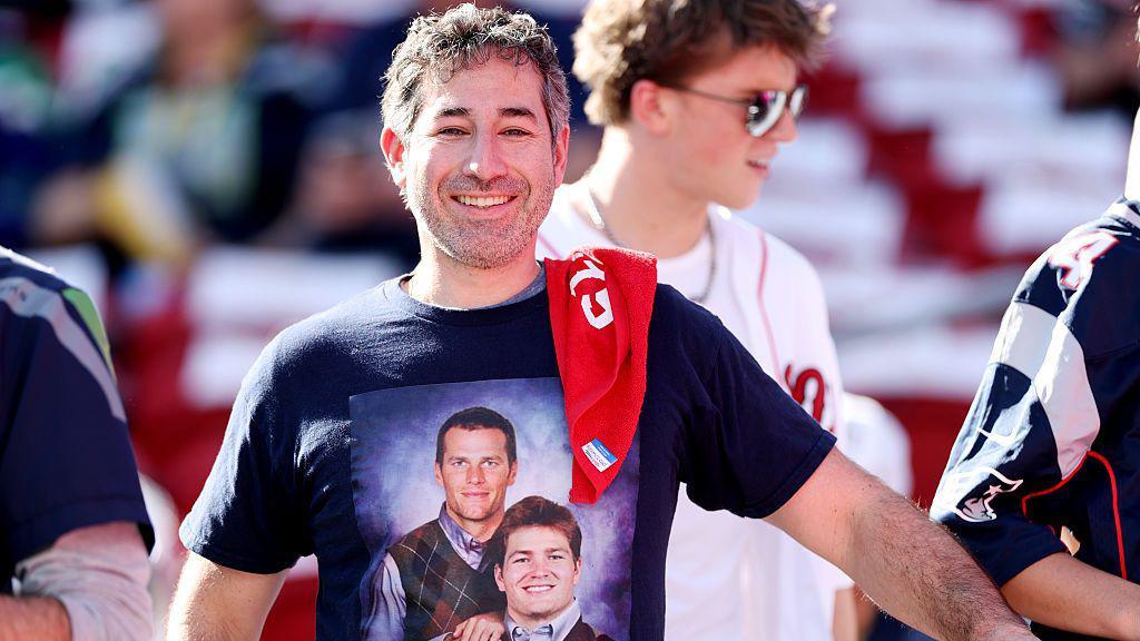 A fan wearing a t-shirt with Tom Brady and Drake Maye on