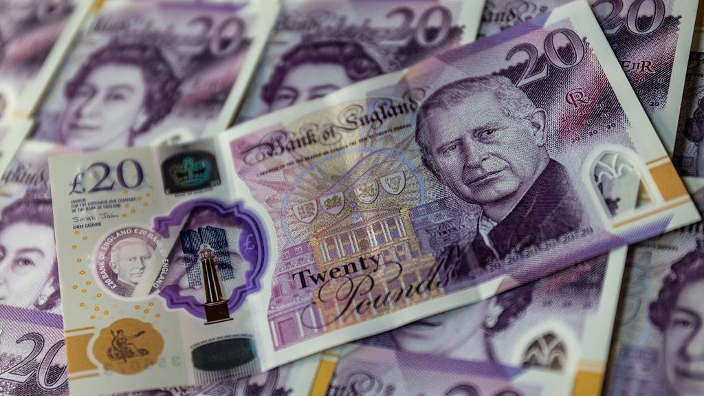 A pile of money. English £20 notes with the King and Queen on them.