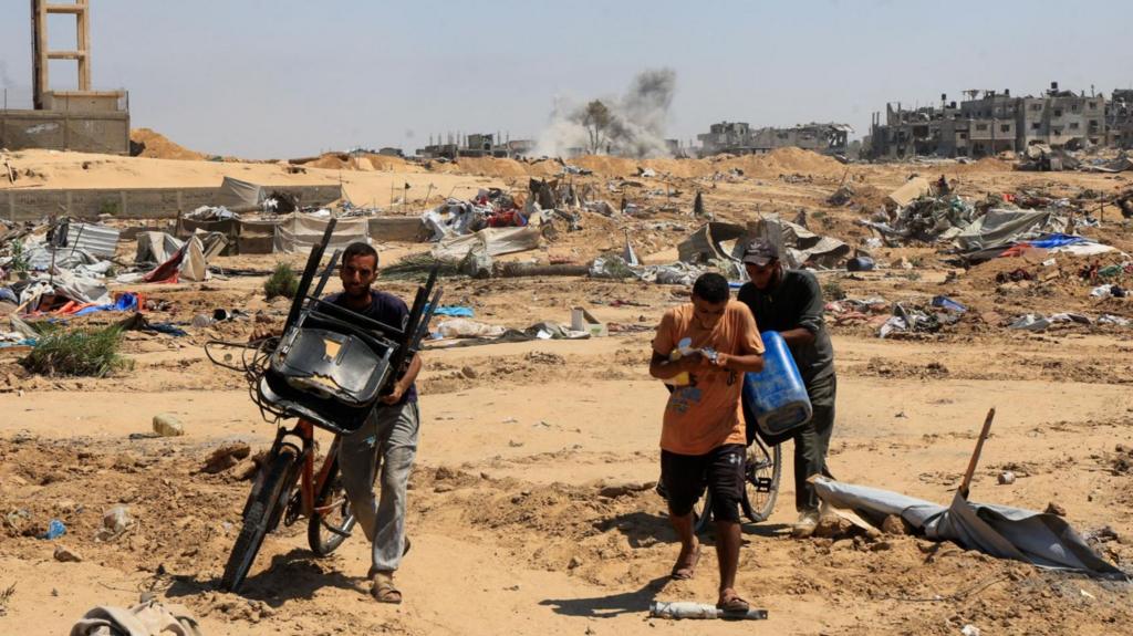 Displaced Palestinian walk with their belongings in the aftermath of an Israeli military operation in Deir Al-Balah