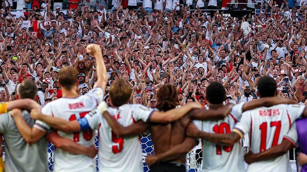 An image taken from behind the England players as they sing Wonderwall with the England fans after beating Norway