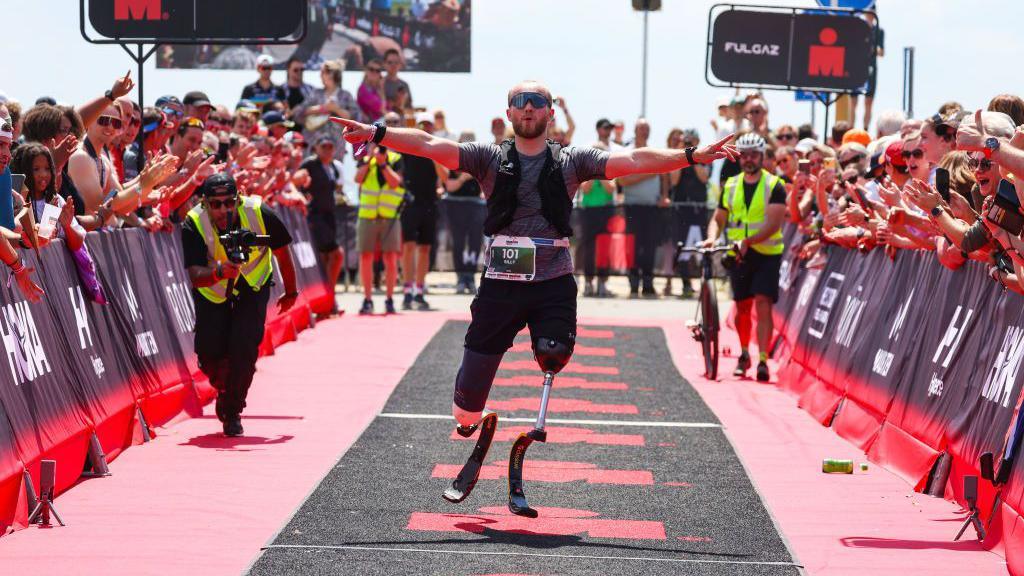 Billy Monger of Britain reacts after finishing Ironman 70.3 Westfriesland he has his arms outstretched as crowds cheer him on in the sunshine