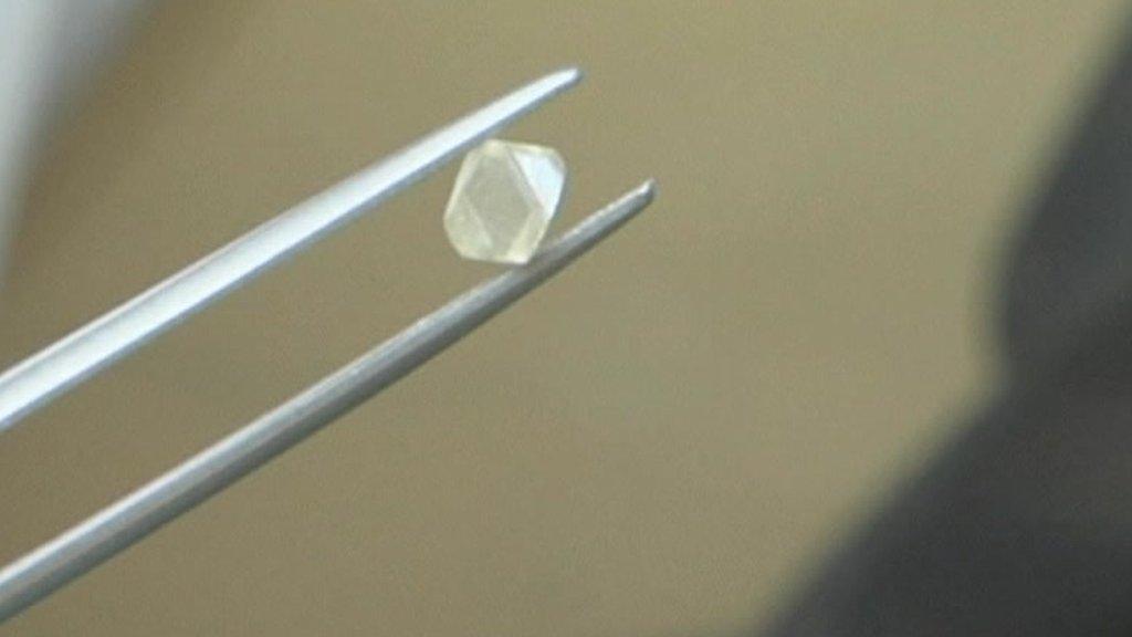 A diamond being held with tweezers