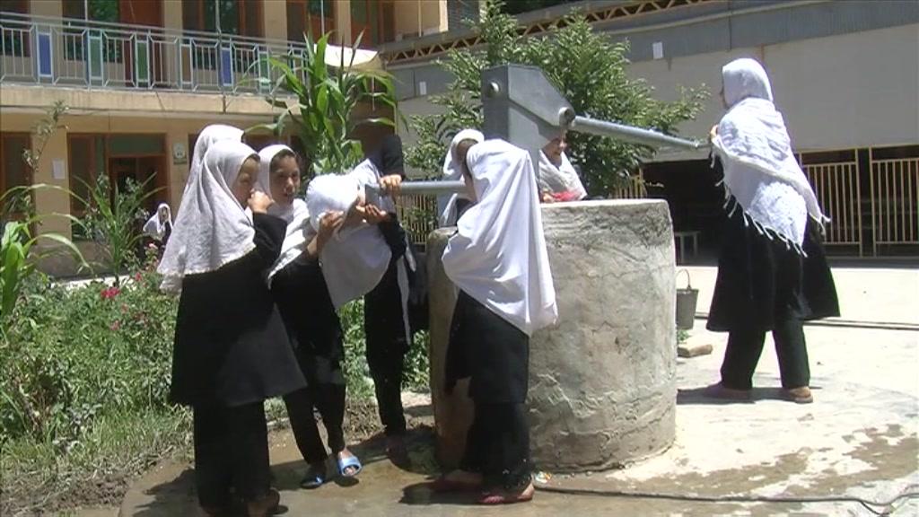 Afghan schoolgirls use a water well