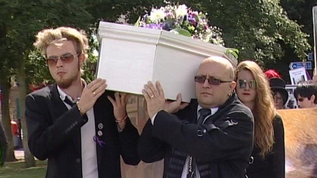 Two men carry a coffin as part of Save the Harlan Beagles' march through Cambridge