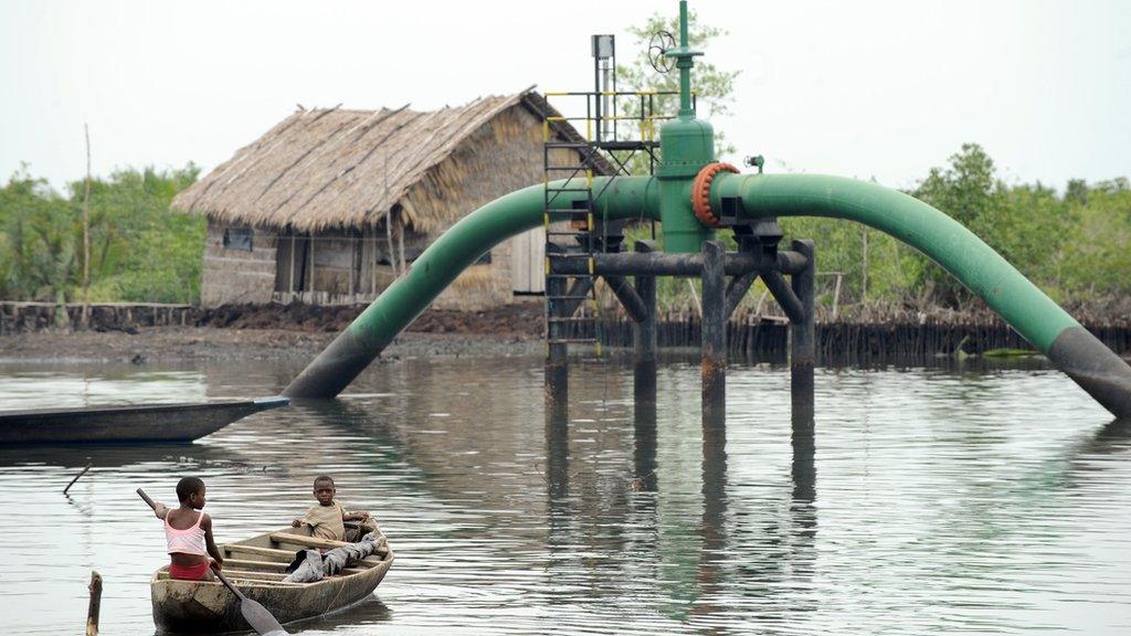 Children in a boat pass an oil pipeline head near their home in Rivers state April 2011