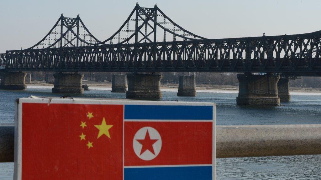 A sign displaying the Chinese (L) and North Korean (R) flags is pictured beside the Sino-Korean Friendship Bridge which leads to the North Korean town of Sinuiju, on the banks of the Yalu River, in Dandong on February 7, 2013.