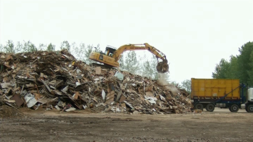 A mechanical digger on a pile of industrial waste