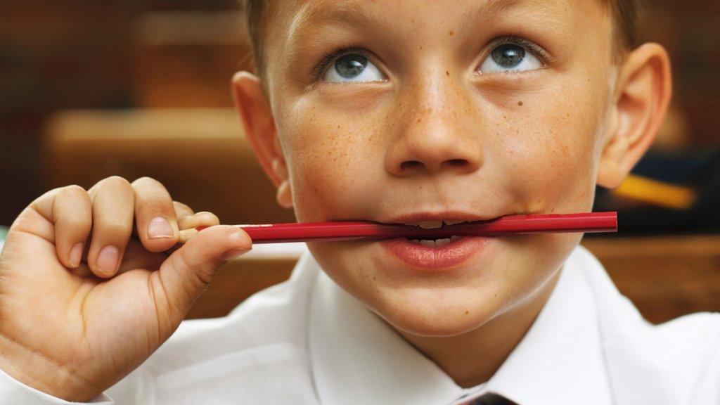 A boy thinking with a pencil in his mouth