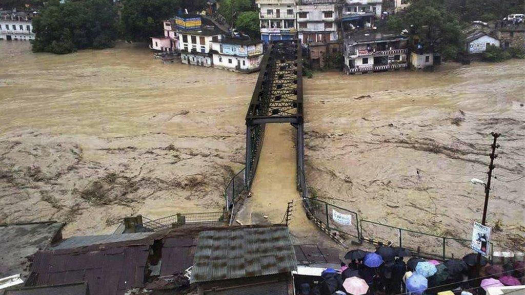 A bridge and homes submerged in the flooded water of the River Ganges in Rudraprayag