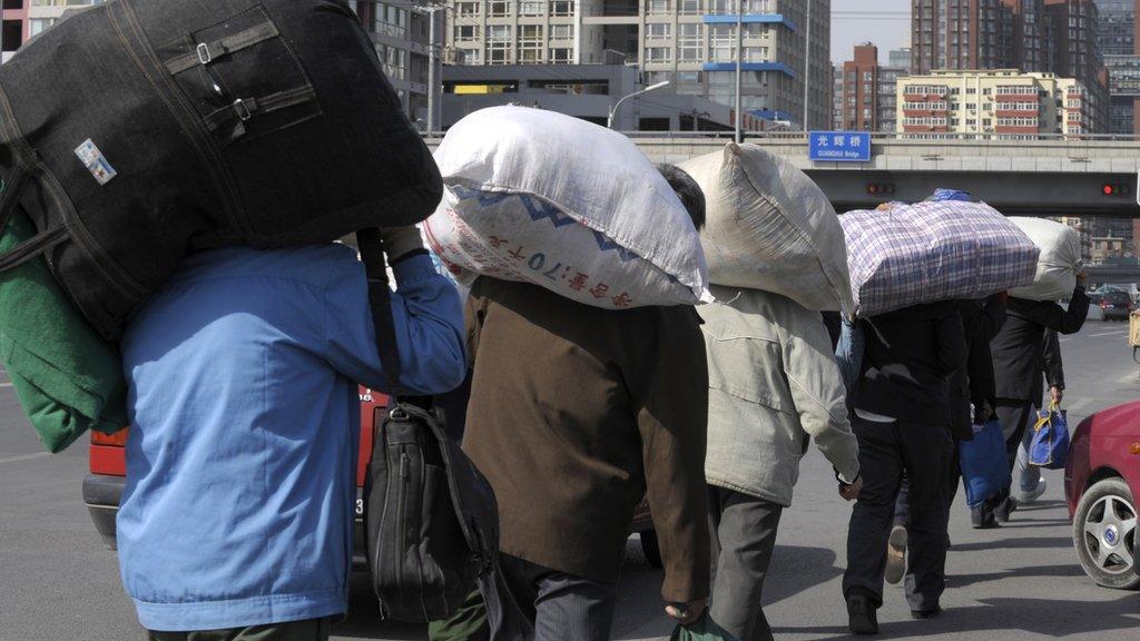 File photo: migrant workers carrying their luggage through a street in Beijing, 25 March 2009