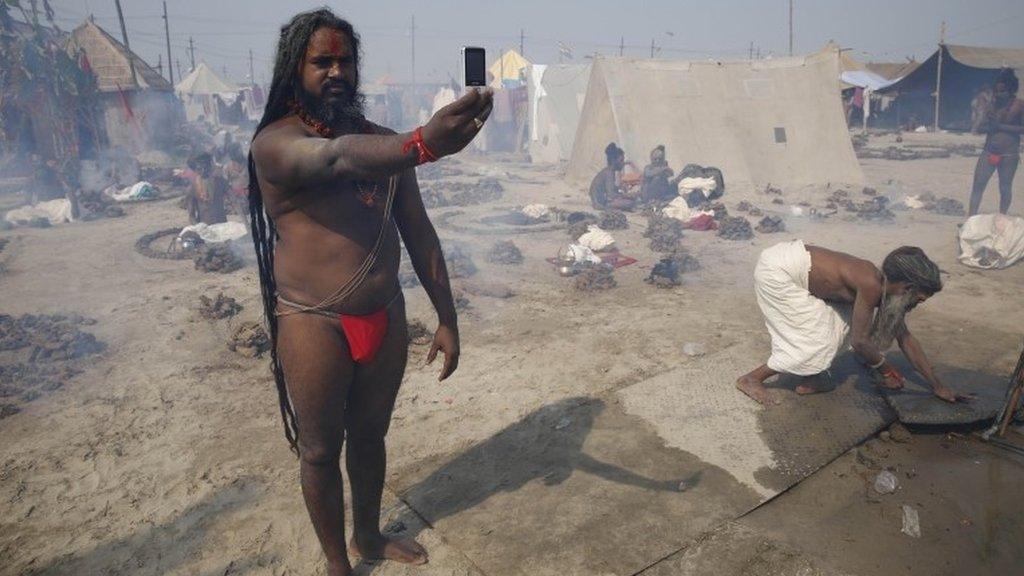 A Hindu holy man takes a selfie on a mobile phone at Sangam in Allahabad, India, Tuesday, Feb. 4, 2014