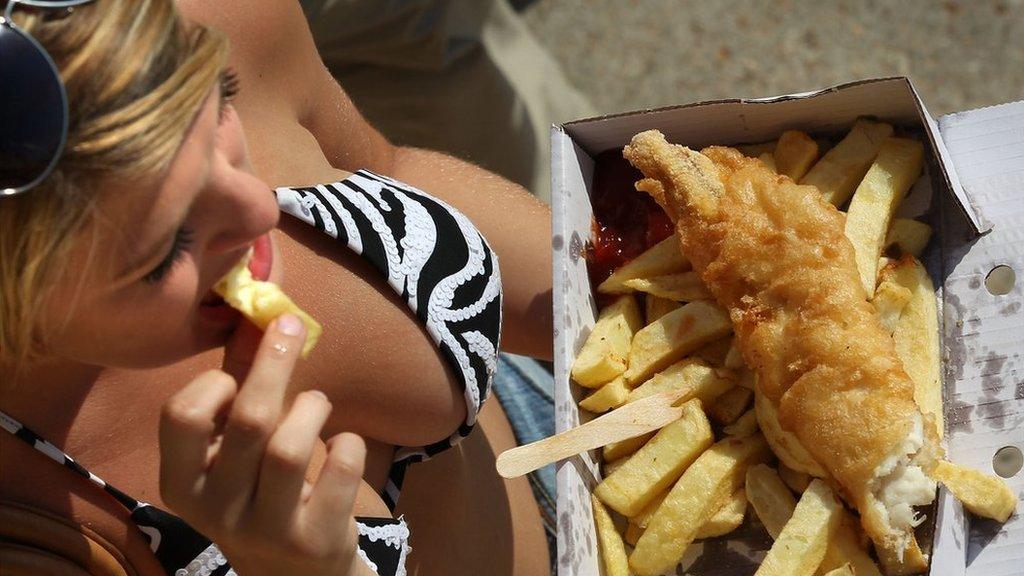 Woman eating fish and chips on beach