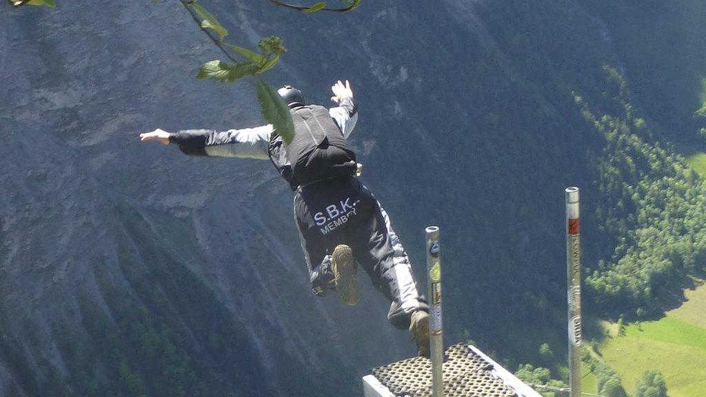 A base jumper jumps off a cliff