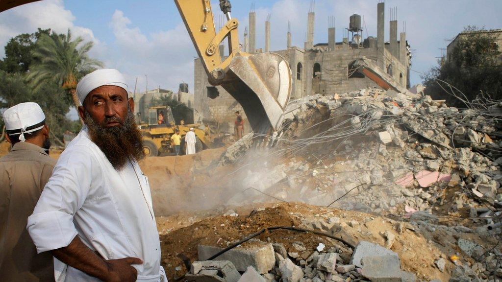 A man watches as a bulldozer sifts through wreckage of a home destroyed overnight in Khan Younis, Gaza