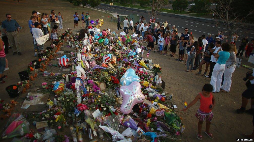 People visit a memorial set up near the cinema